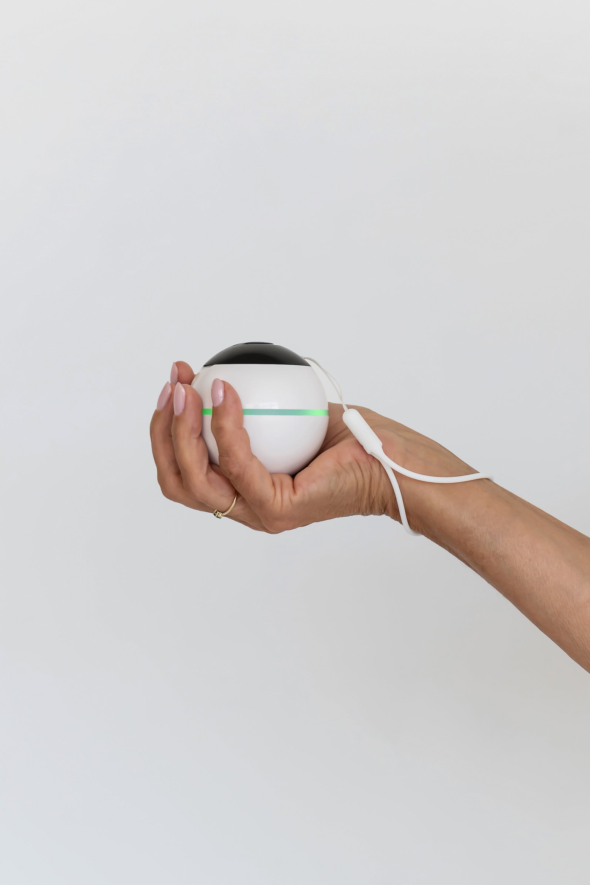 Habeo handheld device for essential tremor relief, being used in one hand.